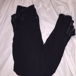 Black jeans with zippers at bottoms.